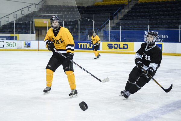 Players from opposing teams wearing black and yellow Blind Hockey league uniforms chase the puck down the ice during the Carnegie Cup elite Blind Hockey Series.