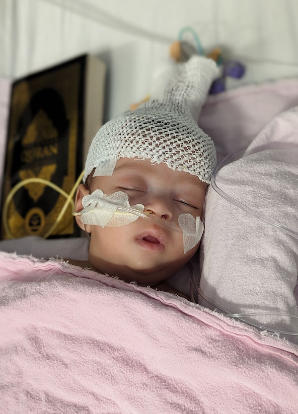 Maryam Fatima in a hospital bed on the day of her first procedure in February, 2024, draped in pink cotton blankets with a Quran next to her.