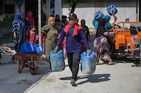 Villagers carry jerrycans to collect clean water distributed by the Indonesian Red Cross (PMI) in Batangan village, Bangkalan Regency, East Java Province on July 21, 2026, as residents struggled to access groundwater in their homes due to a prolonged dry season - linked to this year's El Nino weather phenomenon. (Photo by JUNI KRISWANTO / AFP via Getty Images)