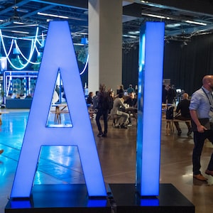 People walk past an AI sign at the All In artificial intelligence conference Thursday, Sept. 28, 2023 in Montreal.THE CANADIAN PRESS/Ryan Remiorz