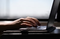 FILE - This May 18, 2021, photo shows a person typing on a laptop on a train in New Jersey. (AP Photo/Jenny Kane, File)