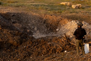 An Israeli police officer surveys the aftermath of an Iranian ballistic missile attack yesterday.