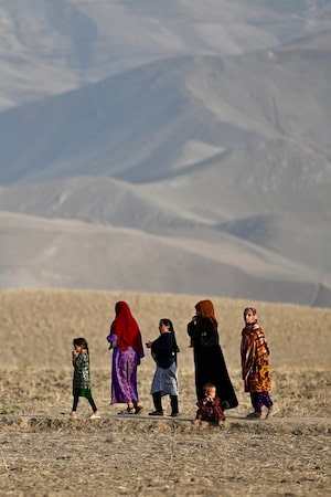 Afghan women and children walk along the foothills on the outskirts of Fayzabad district in Afghanistan's Badakhshan province on July 27, 2026. (Photo by Wakil Kohsar / AFP via Getty Images)