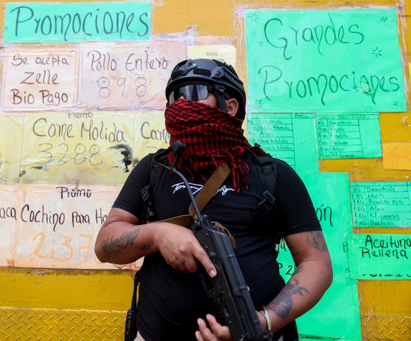 A day after Nicolás Maduro’s capture, one of his armed supporters patrols a store in Caracas to stop speculative pricing. The country's interim president is working with Washington on a major economic overhaul.