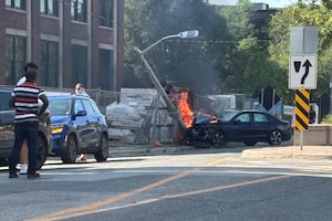 A car is in flames after crashing into a light pole on Laird Drive in Toronto's east end on May 19, 2026.