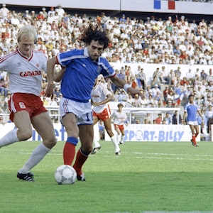 French soccer player Dominique Rocheteau tries to protect the ball from Canadian Ian Bridge during the first half of the group C World Cup opening game, 01 June 1986 in Mexico. (Photo credit should read STAFF/AFP via Getty Images)
