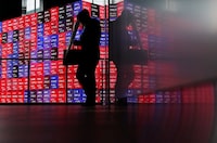 A man walks in front of an electronic screen displaying Japan's Nikkei stock prices quotation board inside a conference hall in Tokyo, Japan, April 27, 2026.  