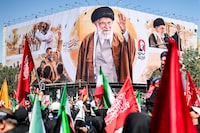 Mourners gather near a giant billboard depicting Iran's slain supreme leader Ali Khamenei at Enghelab Square in Tehran on Monday.