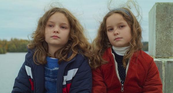 Petite Maman (2021). Shown: Joséphine Sanz and Gabrielle Sanz. After her grandmother dies, Nelly (Joséphine Sanz) is taken to her mother’s childhood home. While her parents go about cleaning out the house, Nelly explores the surrounding woods. She encounters Marion (Gabrielle Sanz), a girl exactly Nelly’s age and to whom she bears a striking resemblance. The pair become fast friends, constructing a hut together, sharing lunches, and talking over the life transitions both are in the midst of. (Marion is only days away from going to hospital for an operation.) Incrementally, the girls’ eerie similarities yield revelations that merge events of the past with those of the present. Courtesy of Elevation Pictures