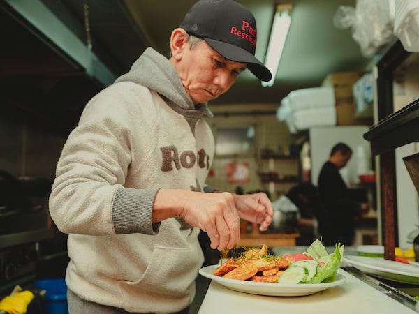 Pat Vann plating a dish of Phanaeng Kai (red curry chicken) in the kitchen of his restaurant in Kingston. (Johnny C.Y. Lam for the Globe and Mail)