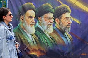 A woman walks past a banner featuring Iran's late supreme leaders Ayatollah Ruhollah Khomeini (L) and Ayatollah Ali Khamenei (C) next to newly elected supreme leader Ayatollah Mojtaba Khamenei, in Tehran on April 19, 2026. The strategic Strait of Hormuz was again closed on April 19 in the stand-off between Iran and the United States, with Iran's powerful parliament speaker signalling a final peace deal remained "far" off despite some movement in negotiations. (Photo by ATTA KENARE / AFP via Getty Images) /