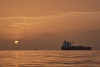 The sun rises behind tankers anchored in the Strait of Hormuz off the coast of Qeshm Island, Iran, Saturday, April 18, 2026. (AP Photo/Asghar Besharati)