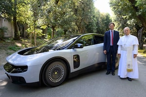 TOPSHOT - This handout photo taken on May 26, 2027 and made available by the Ferrari Press Office on May 27, 2026 shows Pope Leo XIV and Ferrari chairman John Elkann posing by Ferrari's first fully electric model 'Luce' during the car's presentation to the Pope at his residence in Castel Gandolfo. Italian luxury carmaker Ferrari has unveiled its first fully electric model, the Luce, belatedly joining rivals like Porsche and Lamborghini to offer clean-energy driving thrills. With a massive 122 kWh battery, it offers a range of over 530 kilometres and weighs 2.26 tonnes. With fast charging, the vehicle can reach an 80 percent charge from 10 percent in 20 to 25 minutes, the company claims. (Photo by Handout / FERRARI PRESS OFFICE / AFP via Getty Images) / RESTRICTED TO EDITORIAL USE - MANDATORY CREDIT "AFP PHOTO / FERRARI PRESS OFFICE / HANDOUT" - NO MARKETING NO ADVERTISING CAMPAIGNS - DISTRIBUTED AS A SERVICE TO CLIENTS