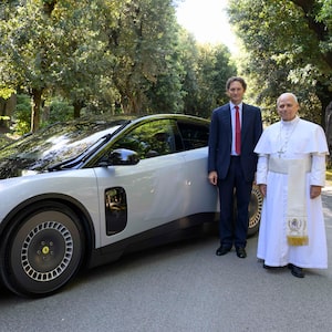 TOPSHOT - This handout photo taken on May 26, 2027 and made available by the Ferrari Press Office on May 27, 2026 shows Pope Leo XIV and Ferrari chairman John Elkann posing by Ferrari's first fully electric model 'Luce' during the car's presentation to the Pope at his residence in Castel Gandolfo. Italian luxury carmaker Ferrari has unveiled its first fully electric model, the Luce, belatedly joining rivals like Porsche and Lamborghini to offer clean-energy driving thrills. With a massive 122 kWh battery, it offers a range of over 530 kilometres and weighs 2.26 tonnes. With fast charging, the vehicle can reach an 80 percent charge from 10 percent in 20 to 25 minutes, the company claims. (Photo by Handout / FERRARI PRESS OFFICE / AFP via Getty Images) / RESTRICTED TO EDITORIAL USE - MANDATORY CREDIT "AFP PHOTO / FERRARI PRESS OFFICE / HANDOUT" - NO MARKETING NO ADVERTISING CAMPAIGNS - DISTRIBUTED AS A SERVICE TO CLIENTS