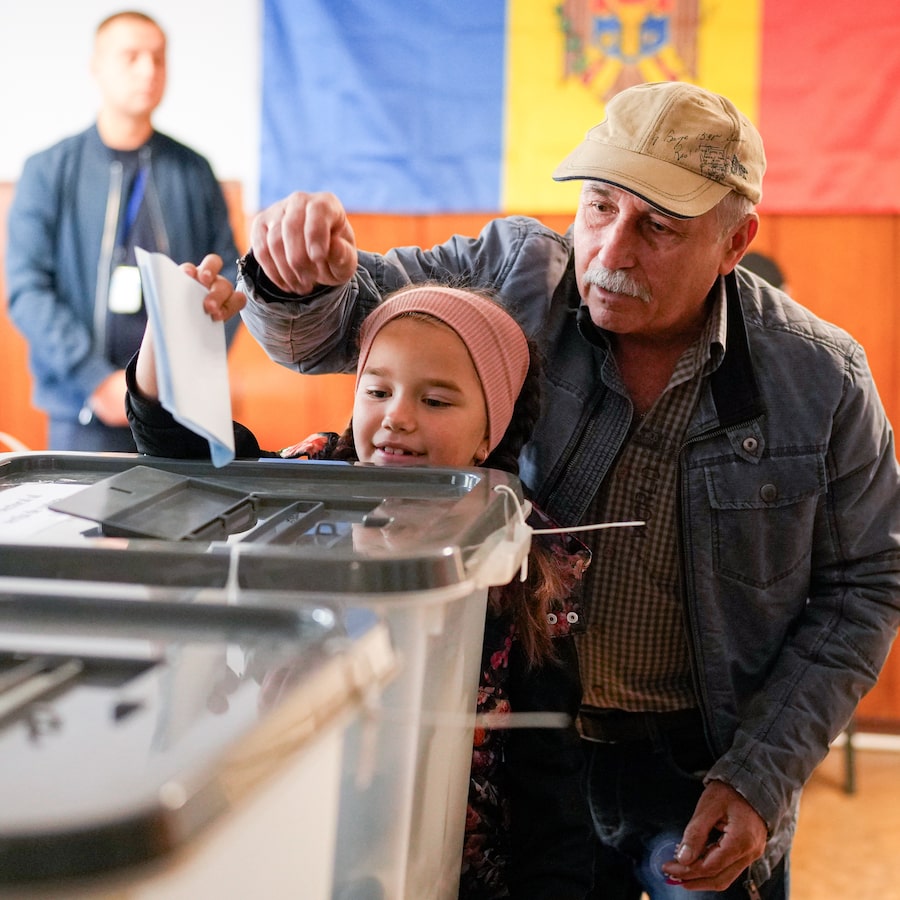 A Moldovan lets a child cast his paper ballot in Chisinau on Sunday, when the country faced a choice between a governing pro-EU bloc and a pro-Moscow opposition, settling on the former.