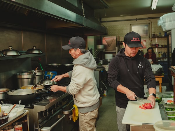Pat Vann (left) cooking with his son Saveth Vann (right) in the kitchen of his restaurant in Kingston. (Johnny C.Y. Lam for the Globe and Mail)
