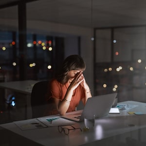 Shot of a young businesswoman looking stressed out while working on a laptop in an office at night