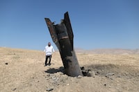 An Israeli ultra-Orthodox Jewish man stands near a part of a missile protruding from the ground, after strikes from Iran, in the central Israeli-occupied West Bank, on Monday.