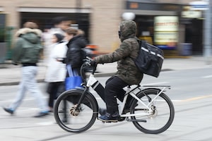 A food delivery courier rides an e-bike in Toronto on January 3, 2024. THE CANADIAN PRESS/Chris Young