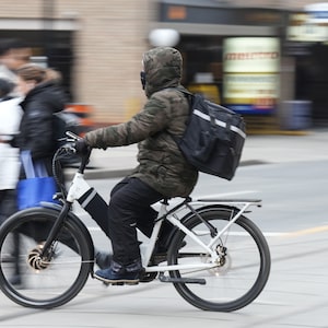 A food delivery courier rides an e-bike in Toronto on January 3, 2024. THE CANADIAN PRESS/Chris Young