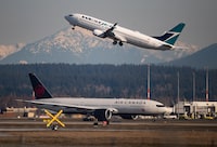 An Air Canada flight departing for Toronto, bottom, taxis to a runway as a WestJet flight bound for Palm Springs takes off at Vancouver International Airport, in Richmond, B.C., on Friday, March 20, 2020. THE CANADIAN PRESS/Darryl Dyck