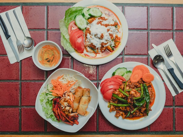 Pat Vann plating a dish of Phanaeng Kai (red curry chicken) in the kitchen of his restaurant in Kingston. (Johnny C.Y. Lam for the Globe and Mail)