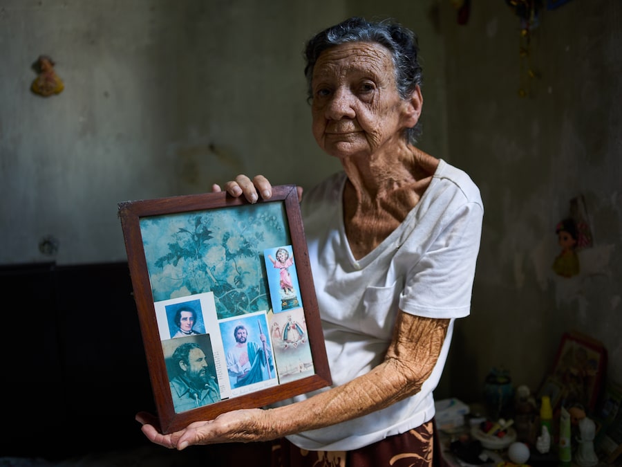 Mercedes Lopez Rey, 83, keeps a portrait of Fidel Castro alongside her prayer cards in Old Havana, where she lives. Life has been harder for seniors like her under an economic crisis and tensions with Washington.
