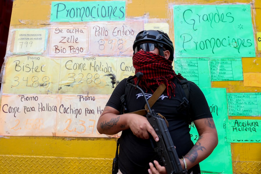 A day after Nicolás Maduro’s capture, one of his armed supporters patrols a store in Caracas to stop speculative pricing. The country's interim president is working with Washington on a major economic overhaul.
