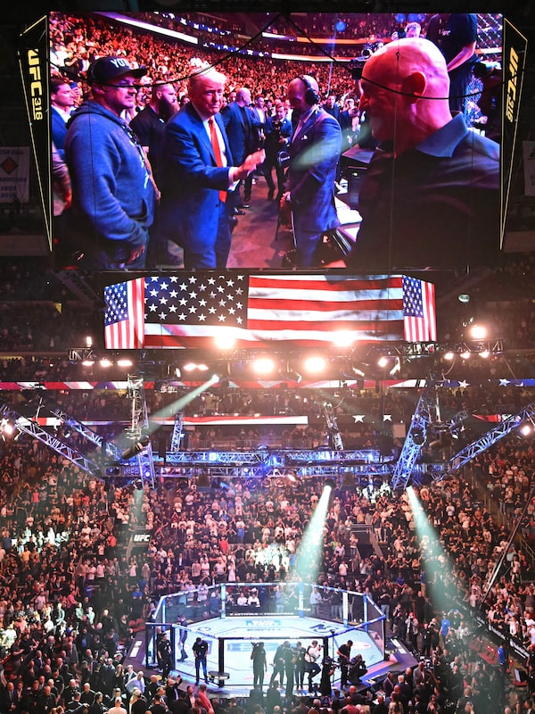 The big screen at the Prudential Center in Newark, N.J., displays U.S. President Donald Trump reaching out to shake hands with Joe Rogan as he attends the UFC 316 event on June 7.