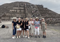 Barbara Welsh, second from the right, pictured with a group of women from B.C., in front of the Teotihuacan Pyramids, in Mexico on Monday, April 20, 2026. The group posed for this picture moments before a gunman opened fire and killed a Canadian woman and hurt 13 other visitors at the site. The shooter can be seen at the top right of the stairs, in a checked shirt and dark pants. THE CANADIAN PRESS/Handout — Barbara Welsh (Mandatory Credit)