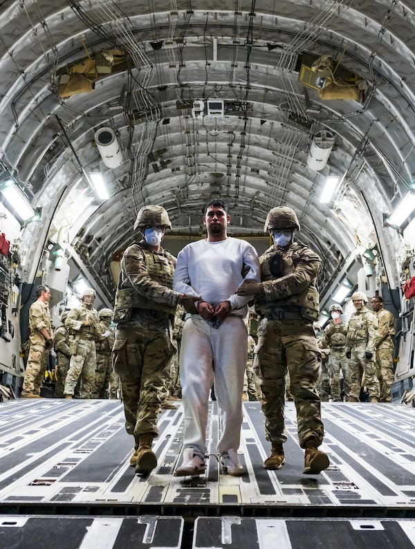 U.S. military personnel at El Salvador International Airport on April 12 escort one of the alleged gang members the U.S. deported to be imprisoned at El Salvador's Terrorism Confinement Center (CECOT).