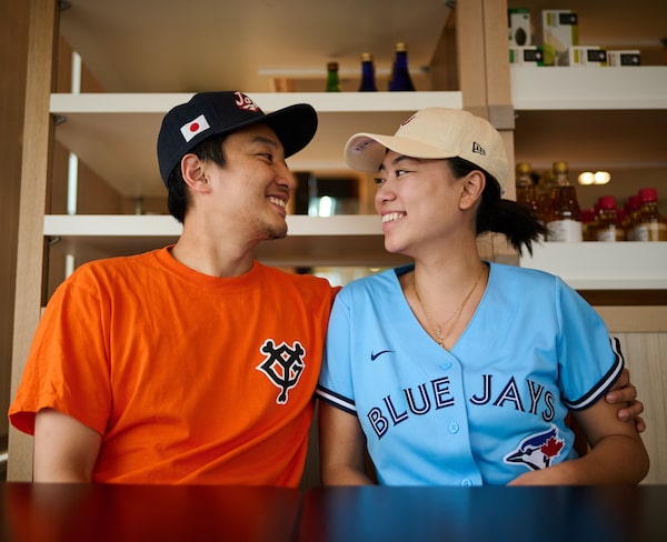 Sean Akiyama and Nicole Lin, dressed in baseball gear at his father’s seafood restaurant, say they’re looking forward to cheering on the Toronto Blue Jays as Kazuma Okamoto joins the roster.