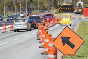 A standard move left sign and a digital flashing arrow with traffic cones advises all traffic to move into the left lane. Shot shallow dof with focus on foreground arrow sign.