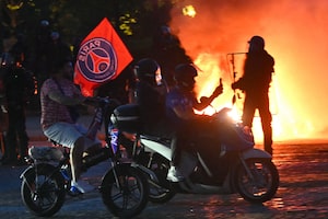 PSG supporters drive their scooters past anti-riot police officers (Rear R) as they celebrate their team's win in the UEFA Champions League final between Paris Saint-Germain (PSG) and Arsenal FC played in Budapest, at Place du Trocadero in Paris on May 30, 2026. (Photo by LOU BENOIST / AFP via Getty Images)