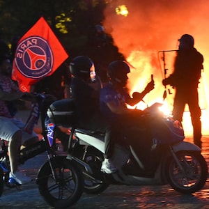 PSG supporters drive their scooters past anti-riot police officers (Rear R) as they celebrate their team's win in the UEFA Champions League final between Paris Saint-Germain (PSG) and Arsenal FC played in Budapest, at Place du Trocadero in Paris on May 30, 2026. (Photo by LOU BENOIST / AFP via Getty Images)
