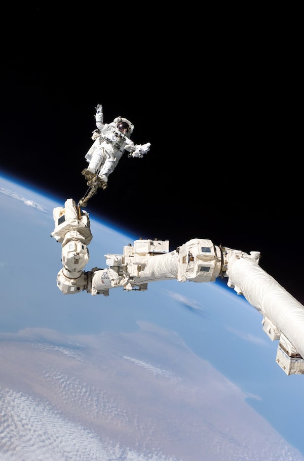 Mission STS-114 was known as 'The Return to Flight,' being the first shuttle launch since the Columbia tragedy. Among its many tasks, Canadarm2 assisted astronauts during their spacewalks. In this image, NASA astronaut Stephen Robinson is held aloft by Canadarm2 during the crew’s third spacewalk.