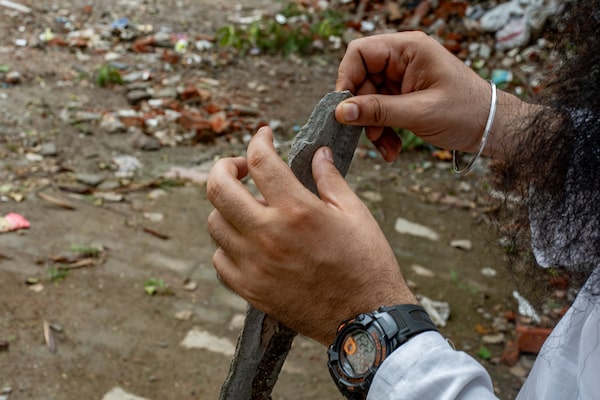Raja Singh picks up an asbestos roofing tile at a dump in central New Delhi, India on September 24, 2023. If not properly disposed of, asbestos fibres can become airborne and potentially cause health problems.