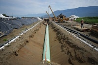 Workers lay pipe during construction of the Trans Mountain pipeline expansion on farmland, in Abbotsford, B.C., on Wednesday, May 3, 2023. The CEO of Pembina Pipeline Corp. says the company needs a resolution of uncertainties surrounding the Trans Mountain expansion project before deciding whether to make an offer for an equity stake in the pipeline. THE CANADIAN PRESS/Darryl Dyck