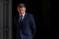 French President Emmanuel Macron walks to greet Cecile Kohler and Jacques Paris, two French nationals freed by Iran after three and a half years in detention, at the Elysee Palace in Paris, France, April 8, 2026. (Tom Nicholson/Pool Photo via AP)