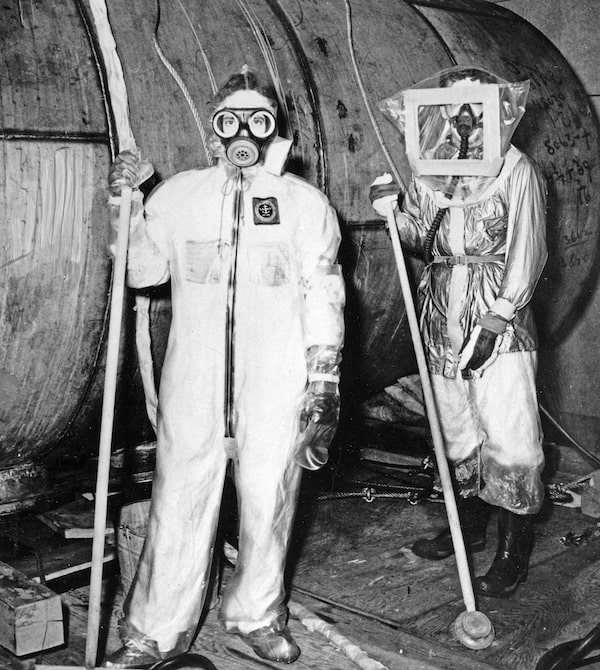 CHALK RIVER DECONTAMINATION -- PROTECTIVE CLOTHING — Plastic suits and respirators are used to protect workers at Canada's Chalk River atomic plant from deadly radioactivity, February 12, 1954. Here are two workers wearing the protective clothing after the big reactor sprang a leak 15 months ago in December 1952. They had to dismantle the reactor and decontaminate the building of radioactive particles. CP PHOTO
