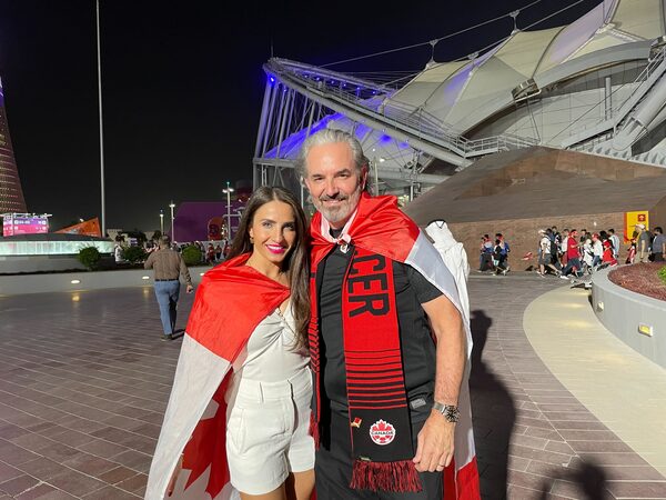 Sarah and Les Woods pose outside the Khalifa International Stadium in Doha. They both have Canadian flags draped on their shoulders.