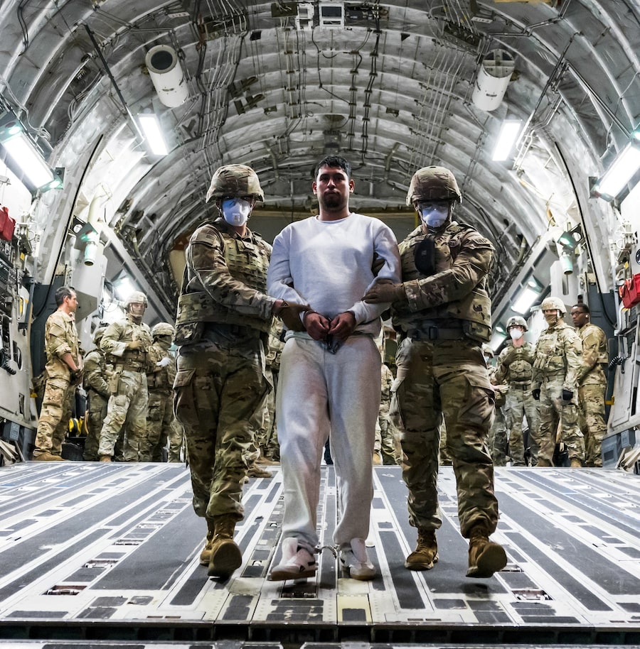 U.S. military personnel at El Salvador International Airport on April 12 escort one of the alleged gang members the U.S. deported to be imprisoned at El Salvador's Terrorism Confinement Center (CECOT).