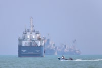 A small motorboat passes anchored vessels in the Strait of Hormuz off Bandar Abbas, Iran on Thursday. The proposed memorandum of understanding calls for reopening the strait and lifting the U.S. naval blockade on Iranian ports.