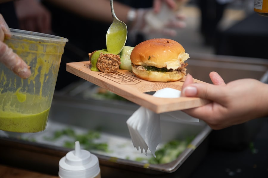 Sous chef Damian Fellin of George restaurant adds sauce to a guest's apricot and miso wild boar sausage at Brewery & the Beast festival in Toronto on July 26