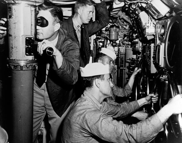 Lt. James "Jimmy" Carter, background, peers at instruments in main control room of the submarine USS K-1 (SSK-1) between June and October 1952. He served as executive officer, engineering officer, and electronics repair officer on the SSK-1. When Admiral Hyman G. Rickover (then a captain) started his program to create nuclear-powered submarines, Carter wanted to join the program and was interviewed and selected by Rickover. Carter was promoted to lieutenant and from 3 November 1952 to 1 March 1953, he served on temporary duty with the Naval Reactors Branch, U.S. Atomic Energy Commission, Washington, D.C., to assist "in the design and development of nuclear propulsion plants for naval vessels." Courtesy of Naval History and Heritage Command