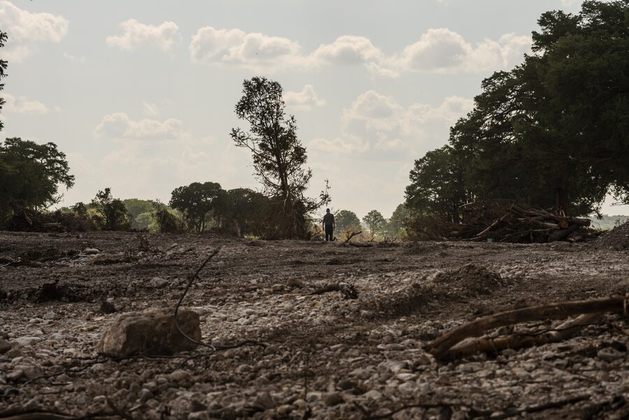 A man walks along the bank of the Guadalupe River in Kerville, Tex., after flood waters have receded.