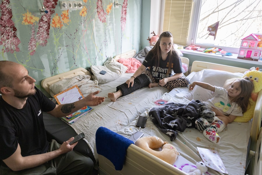 Afina Didichenko, 3, throws a paper airplane past her mother, Mariia, to her father, Yevhenii. All three have vivid memories of the Russian missile strike on their Ukrainian hometown, Kryvyi Rih, that injured Afina and Mariia earlier this month.