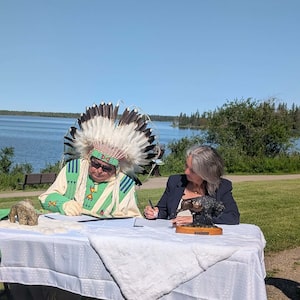 Minister Julie Dabrusin and Elder Leonard Weasel Traveller of the Manitou Asinîy-Iniskim-Tsa Xani Centre sign a Memorandum of Understanding securing land in Elk Island National Park for MAITX to establish a permanent home for the Manitou Stone.