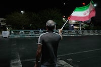 A pro-government demonstrator waves an Iranian flag in a gathering commemorating the late Iranian Supreme Leader Ayatollah Ali Khamenei at a square in Tehran, Iran, Saturday, July 11, 2026. (AP Photo/Vahid Salemi)