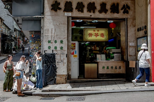 Tourists take a break outside a herbal tea shop on Hollywood Road next to the spot where a long forgotten ghost sign was uncovered by a car crash.